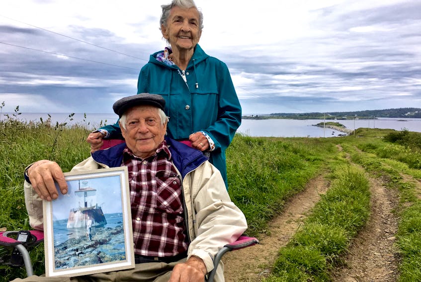 The 62-year bride and groom – Robert and Ethel Cottreau - with Bug Light in the far background. Robert is holding a photo of his family’s home on Bug Light that existed there until 1959.