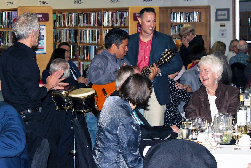 Dr. Shelagh Leahey, right, is serenaded by the trio of Freddy Mujica, Michael Carbonell and Nick Jackson during Dining Among the Stacks on Nov. 2.