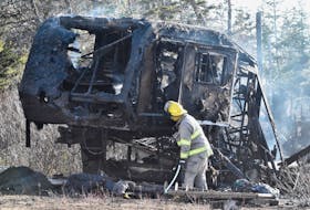 A firefighter looks over the charred remains of a camper trailer. A brush fire on the Hardwood Hills Road in Melbourne, Yarmouth County, spread to a neighbouring property, destroying the trailer that was in the yard of the nearby residence. TINA COMEAU PHOTO