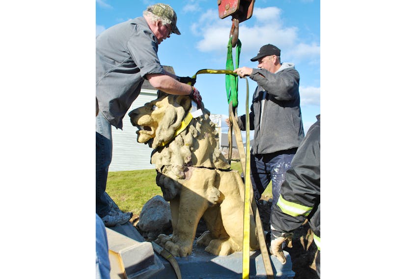 With the help of a backhoe and a crane, Town of Clark’s Harbour public works employees Bryant Newell and Curtis Smith attach straps to the historic Stone Lion, readying it for the move to the town park behind the Town Hall.