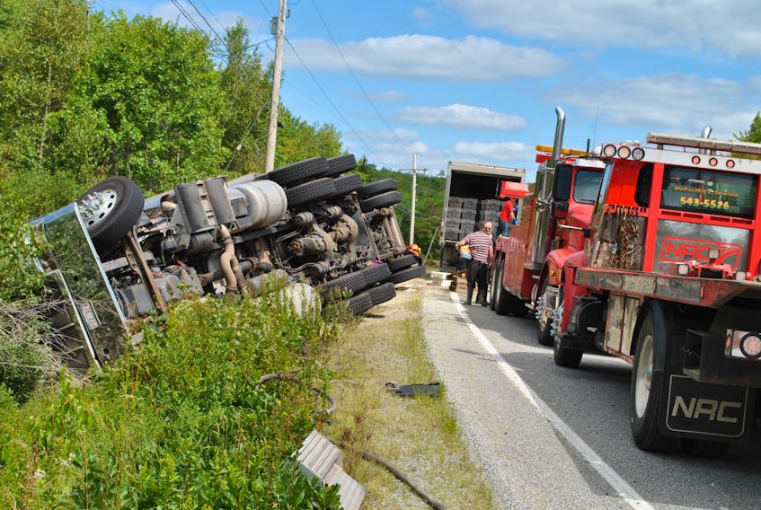 Two wreckers wait to upright a transport trailer that went off the road in Granite Village on Aug. 31, while its cargo of lobster is recovered and transferred to another truck.