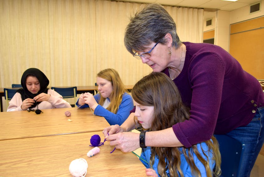Volunteer Cheryll Blinkhorn gives Grade 6 Hillcrest Academy student Rylie Jamieson a helping hand knitting a finger puppet for the IWK. In the background classmates Emma Harris and Shahed Hendawi work on their puppets. KATHY JOHNSON PHOTO