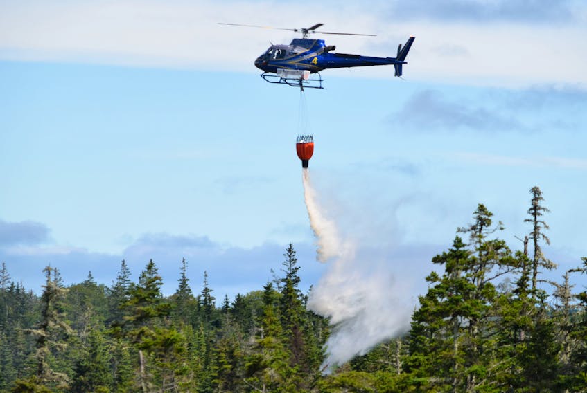 A Lands and Forestry helicopter dumps a bucket of water on the Upper Woods Harbour fire on Sept. 12. The fire was still burning but was under control. KATHY JOHNSON