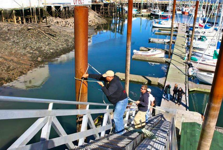 Boat owners Mike Carter, top, and Colin Bondy lash a steel support pylon, hoping to guide its swaying in this file photo from last September at the Digby Yacht Club. FILE PHOTO