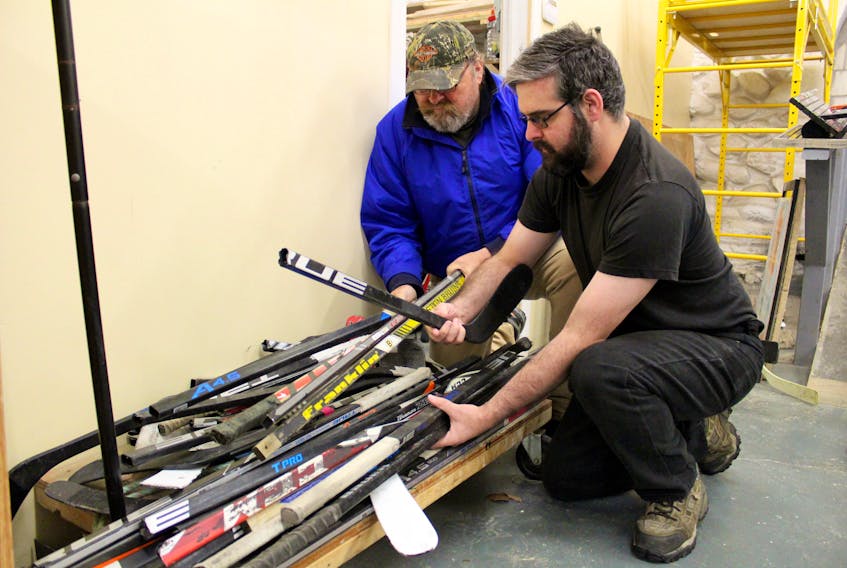 Kevin Ellis (left) and Stephen Davidson sort through some old hockey sticks. The two are among those working on the hockey furniture project at The Store Next Door in Yarmouth.