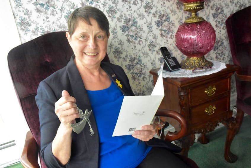Yarmouth resident Sandy Dennis reads a card and holds a gift that someone sent to her to show their support. TINA COMEAU PHOTO