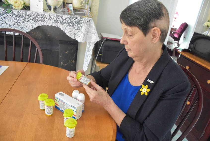 Sandy Dennis looks over some of the pills that she has to take on a daily basis because of her cancer TINA COMEAU PHOTO