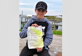 Dallas Goreham holds up the note he found in a bottle on May 16 washed up on the Lower Woods Harbour shoreline, 18 years after it had been tossed into the ocean in the waters off Gloucester, Massachusetts.