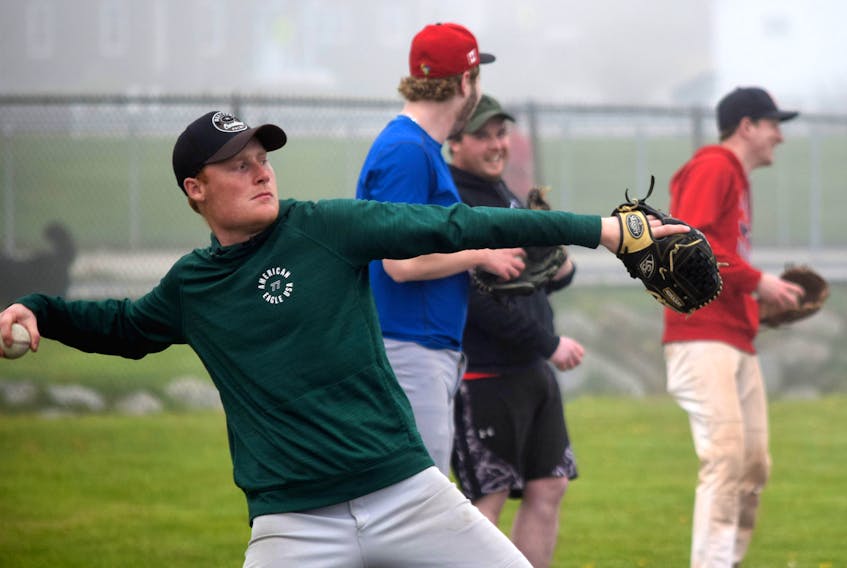 Shelburne Schooners player Ty Ross winds up for a throw while fellow teammates Jarrett Ross, Tristen Reede and Gerry Holle (from left) share a laugh during practice in Clark's Harbour on May 8. The team has several more practices scheduled for Sherose Island before the roster is finalized.
