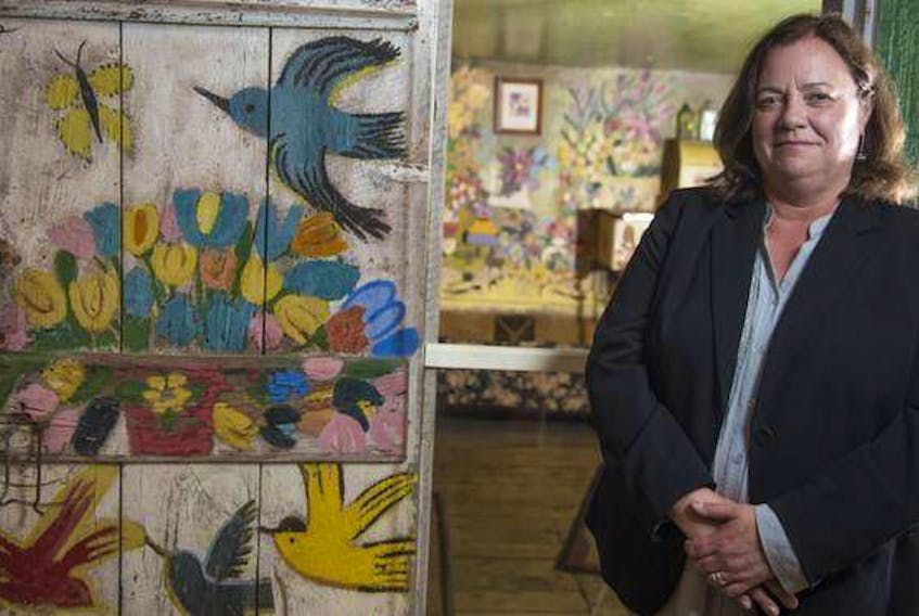 Art Gallery of Nova Scotia's CEO Nancy Noble stands next to Maud Lewis’s painted home.