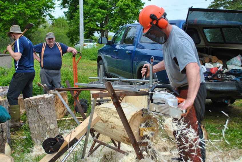Burlin Nickerson uses an Alaskan sawmill to turn logs that will be used at the Nova Scotia Lumberjack Championships in Barrington June 16 and 17. Helping out his dad are Gerald Nickerson and Ryan McIntyre, right, president of the North Nova Lumberjacks Society.