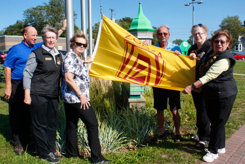 Amherst town councilor Terry Rhindress and Mayor David Kogon are joined by Zonta members Sandie Smith, Carolyn Douglas, Marg E. Smith, Mary Sinclair and Vicki Randall in raising the Zonta flag at a ceremony by the YMCA on Sept. 17. This is Zonta Week in Amherst. - Town of Amherst photo