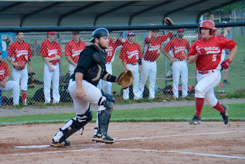 P.E.I. Junior Islanders catchers Jayden McLean waits for a throw as Chatham Ironmen Matt Carroll scores his team's second run of the game Saturday at Memorial Field.