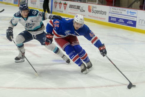 Summerside D. Alex MacDonald Ford Western Capitals forward Marc-Andre LeCouffe, right, protects while cutting to the net on Edmundston Blizzard defenceman Tristan Mercure Thursday at Credit Union Place.