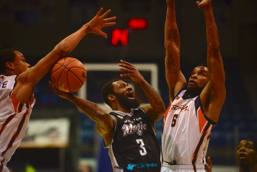 Island Storm teammates Tyree White, left, and Tirrell Baines, right, defend against Moncton Magic's Corey Allmond Monday during National Basketball League of Canada action at the Eastlink Centre.