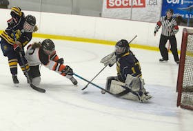 Central Storm forward Molly Doyle, centre, tries to direct a loose puck past Mid-Isle Wildcats goalie Emma Arsenault as Bella Reardon defends Sunday at MacLauchlan Arena in Charlottetown.