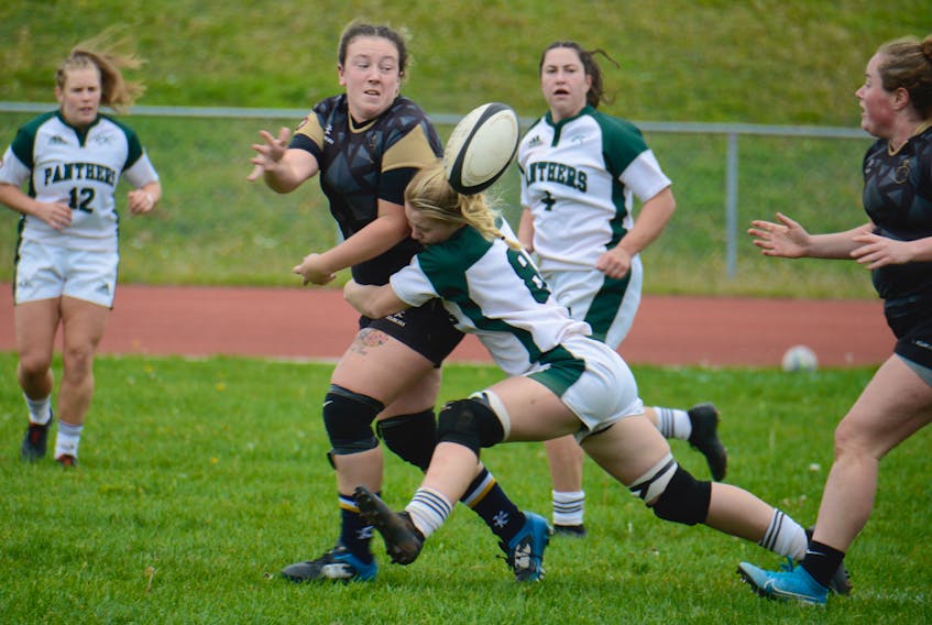 Sarah MacLeod of the Charlottetown Rugby Football Club passes the ball to teammate Frances MacWillam while being tackled by UPEI Panther Julia Freeburn during exhibition women’s rugby action Saturday in Charlottetown.