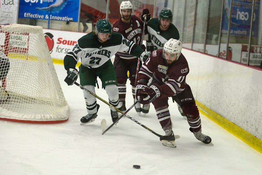 Saint Mary's Huskies winger Sam King, right, and UPEI Panthers defenceman Jesse Annear battle for the puck behind the Panthers net Friday during Atlantic University Sport men's hockey action at MacLauchlan Arena.
