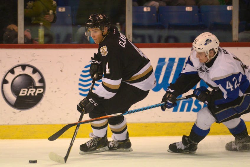 Charlottetown Islanders defenceman Brendon Clavelle, left, fights off the check of Saint John Sea Dogs right-winger Ben Reid Sunday during Quebec Major Junior Hockey League action at the Eastlink Centre.
