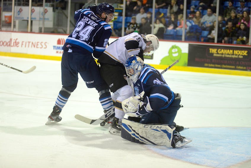 Chicoutimi Sagueneens goalie Alexis Shank looks for a loose puck as Sagueneens defenceman Louis Crevier tries to tie up Charlottetown Islanders left-winger Ethan Crossman Saturday during Quebec Major Junior Hockey League action at the Eastlink Centre.
