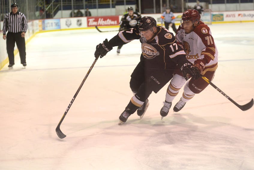 Charlottetown Islanders left-winger Liam Peyton, left, and Acadie-Bathurst Titan defenceman Alec Rheaume go into the corner after a loose puck Friday during Quebec Major Junior Hockey League action at the Eastlink Centre.