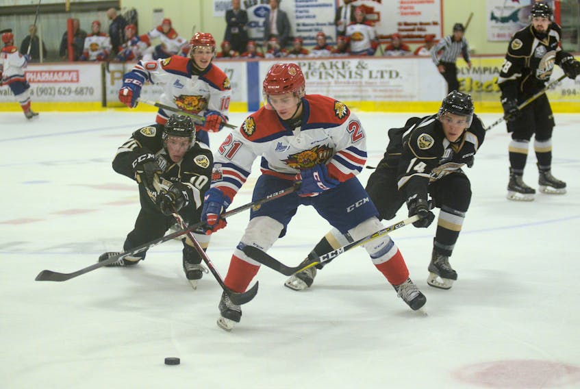 Charlottetown Islanders’ forwards Keiran Gallant, left, and Justin Gill, right, try to get the puck away from Moncton Wildcats’ right-winger Manuel Alberg Tuesday during Quebec Major Junior Hockey League pre-season action in Cornwall, P.E.I.