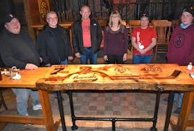 Friends and family gathered for a photo around the table recently installed at The Engine Room to honour former Truro hockey player Randy ‘Dewey’ Dewar, who passed away last August. Pictured are table-designer Dave Manley (left), John Terry who donated the steel-pipe legs, Sterling Mingo who was a teammate of Dewar’s on all three teams referenced in table artwork, Engine Room owner Mimi Woods, Terry Rushton who worked on the table and Dewar’s son Brock. Unavailable for photo was air-brush artist Nathan Harb. 