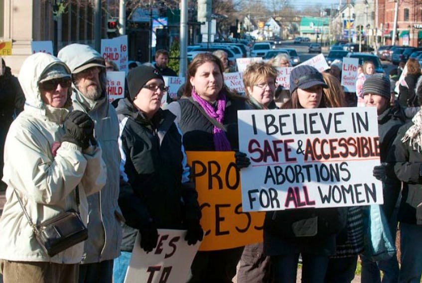 Pro choice advocates hold banners during a rally at Province Houses Saturday. Pro life protesters were also on hand with their banners.