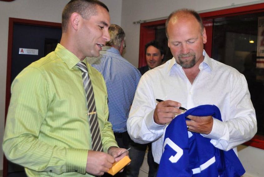 Wendel Clark autographs a sweater for a fan during a pre-dinner reception in the Hall of Fame Room at Acadia Arena