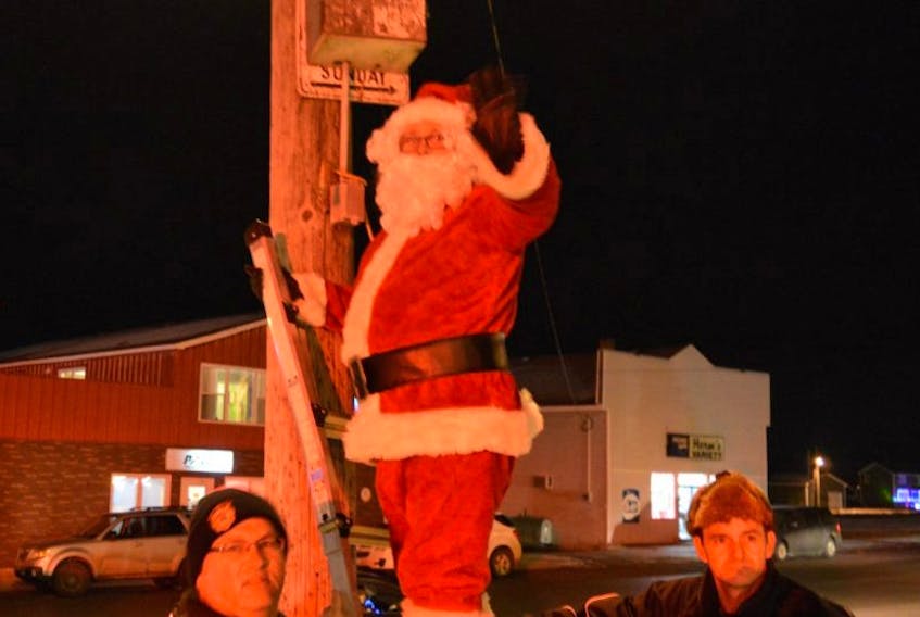 Santa plugging in the lights to officially light up the town of Botwood’s Christmas tree. Helping Santa are Fireman and Councillor Rob Hancock, left and Botwood Mayor Scott Sceviour.