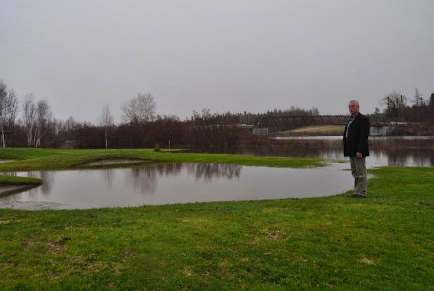 Grand Falls Golf Club executive director Mike Brown stands near a water-filled sand trap near the 18th green. Water from Rushy Brook has risen over its banks and onto the course.
