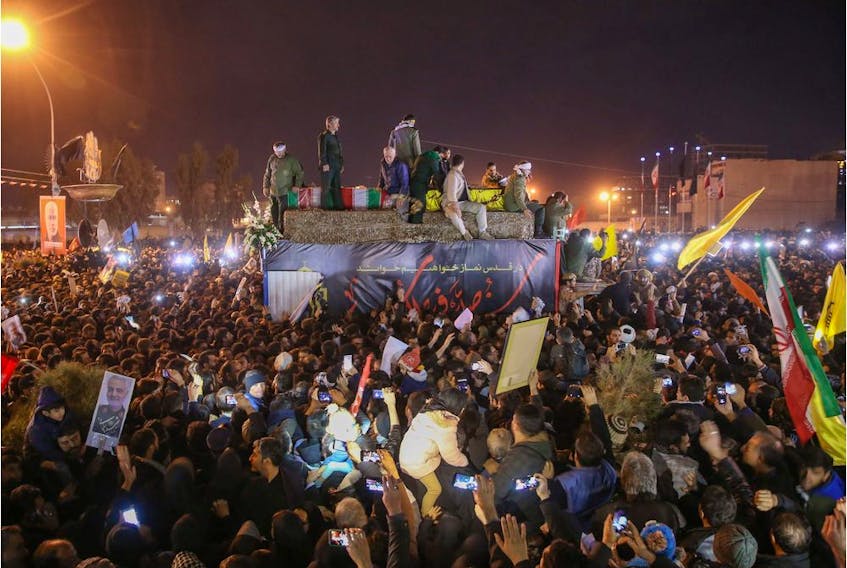 Iranians gather around a vehicle carrying the caskets of slain military commander Qasem Soleimani and others during a funeral procession in the Iranian city of Qom on Jan. 6, 2020.