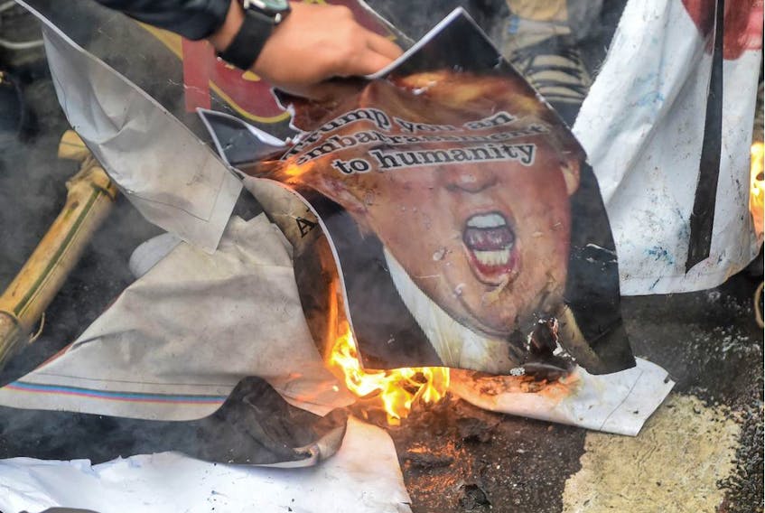 People burn a poster representing US President Donald Trump (C) to protest against the US authorities for the killing of Iranian commander Qasem Soleimani in Iraq, during a demonstration near the US embassy in New Delhi on January 7, 2020. - A US drone strike killed top Iranian commander Qasem Soleimani at Baghdad's international airport on January 3, dramatically heightening regional tensions and prompting arch enemy Tehran to vow "revenge". (Photo by Prakash SINGH / AFP)