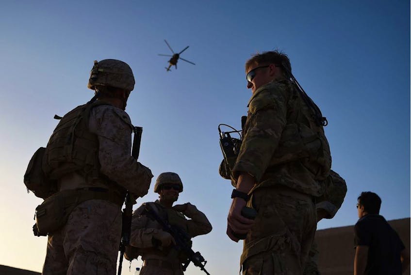 US Marines and Afghan Commandos stand together as an Afghan Air Force helicopter flies past during a combat training exercise at Shorab Military Camp in Lashkar Gah in August 2017.