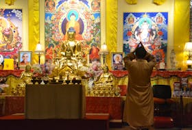 A female nun prays within the Uigg Great Wisdom Buddhist Institute Monastery. A picture of late Master Jih-Chang can be seen on the left.
