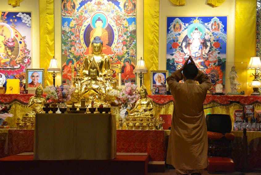 A female nun prays within the Uigg Great Wisdom Buddhist Institute Monastery. A picture of late Master Jih-Chang can be seen on the left.