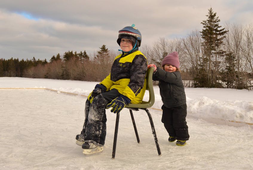 Tucker Strongman, 2, pushes older brother Wallace on the outdoor rink behind the Alberton Fire Department on Feb. 13. Dad James Strongman said the rink “is the best thing that’s in Alberton this year.”