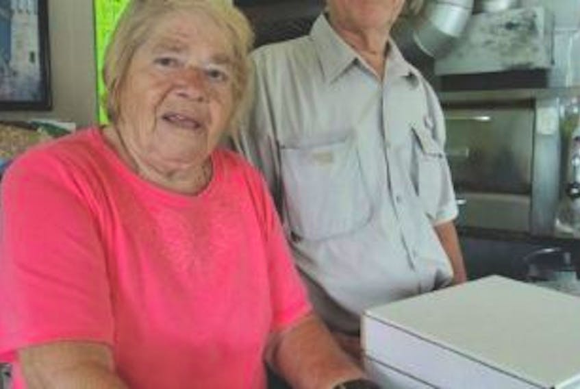 ['Alice Xiros, 82, of Alice’s Pizza would still be working if you could. She stands in the shop, which closed a year ago, with her husband Bob. PHOTO BY ROSALIE MACEACHERN']