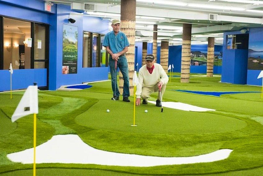 Bob Dowling checks the green before he putts while Pat Rossiter waits his turn recently when the two golfers tried the 18-hole putting course at All About Golf in Charlottetown. The golf course is located in the basement of the Confederation Court Mall and the main store is above.