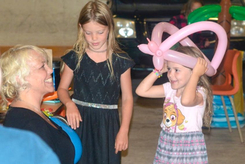 Five-year-old Cali Taggart tries on her new balloon hat while her seven-year-old sister, Ava Taggart waits her turn. Sonya Sarty made balloon hats and animals for kids all day long. Sarty and the Taggart sisters are from Oxford.