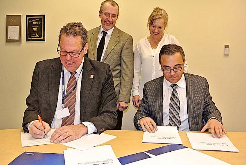 Michel Doucet (left), executive director of continuing education for CCNB, and NSCC senior manager of customized learning Mike Kelloway sign a strategic alliance that will magnify the reach of the Marine Manufacturing Initiative training while NSCC Cumberland academic chair Andy Moore (back, left) and NSCC Cumberland training co-ordinator (business development) Anne Lawrence look on.