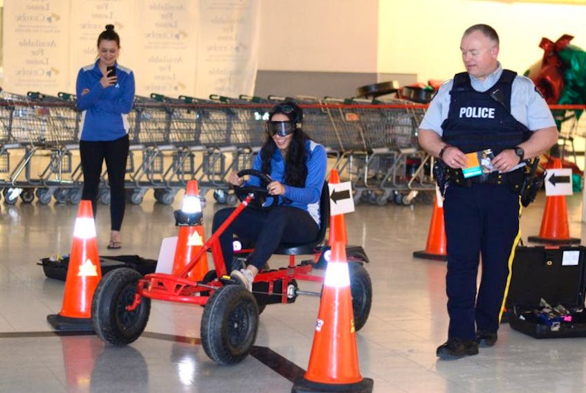 Sonia Minocha wore impairment googles that mimicked driving while impaired by alcohol Wednesday afternoon at the Amherst Centre Mall. RCMP Const. Travise Dow watches her progress while co-worker Emily Rossong snaps a few photos.