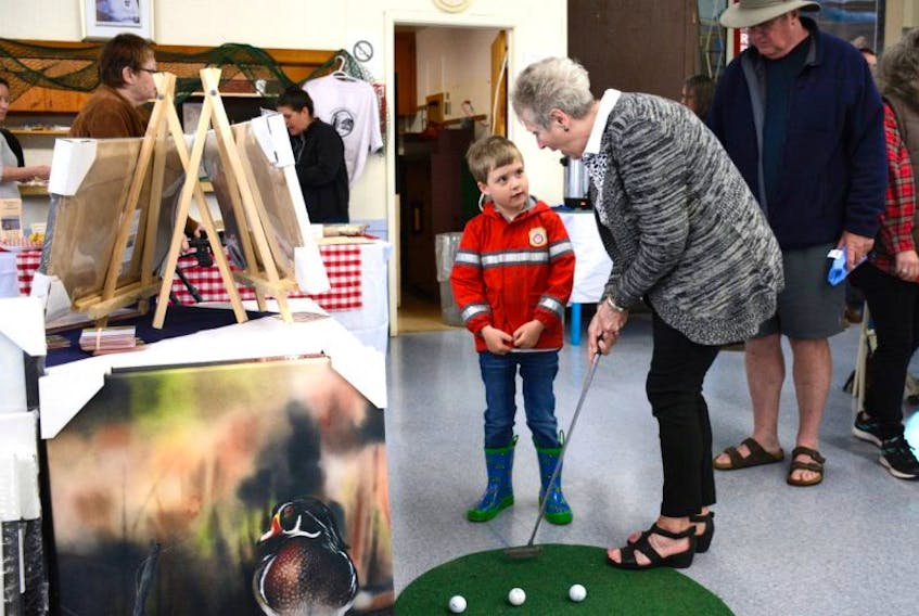 Five-year-old Liam Whitman gets a lesson on how to putt from Kathy LeBlanc, manager of the Parrsboro Golf Club. Liam was at the trade fair with his grandfather, Bob Montague (right).
