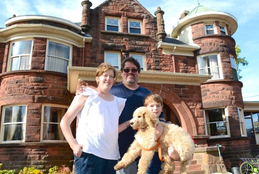 Allison, David and Dylan Marshall stand in front of their Amherst home with their dog, Bailey