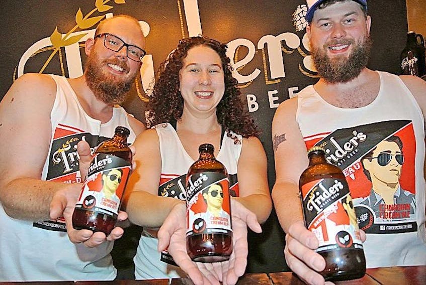 Joe Potter (left), Laura Parker and Scott Parker of Trider’s Craft Beer hold up bottles of Brew-deau Canadian Cream Ale that was named the winner of Propeller Brewing Company’s #BrewPatriotLove contest that is part of the company’s 20th anniversary celebrations.