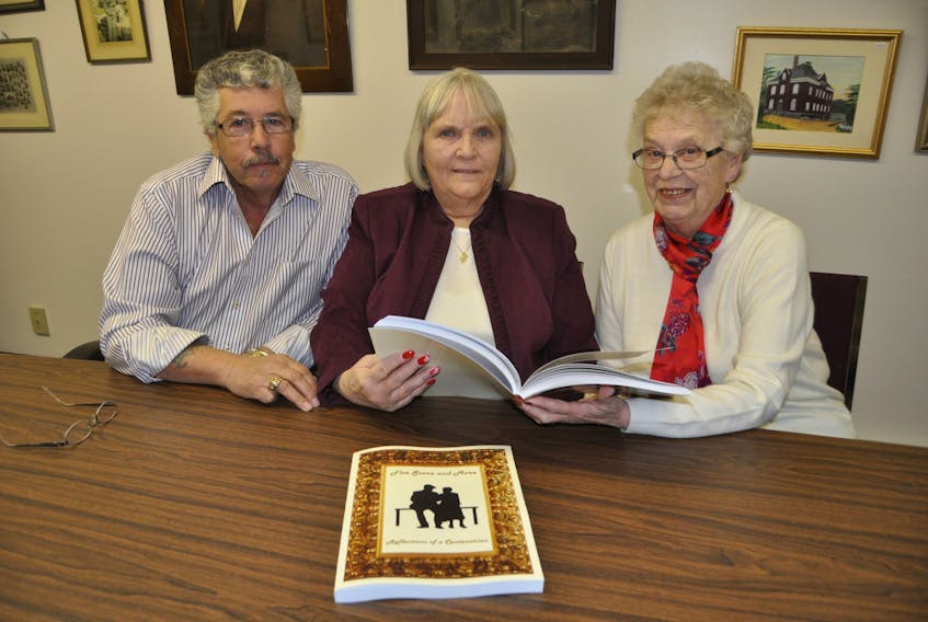 (From left) John Reid, Barb Reid and Phyllis Perry look over Five Score and More, the new book available from the Cumberland County Genealogical Society chronicling the lives of hundreds of centenarians of Cumberland County.