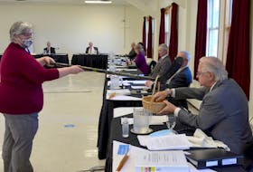 Clerk Carolyn Young distributes ballots to socially-distanced councillors tasked with selecting a new warden and deputy warden for Annapolis County. Coun. Alex Morrison is pictured picking a ballot out of the basket dangling from a hockey stick. - Contributed