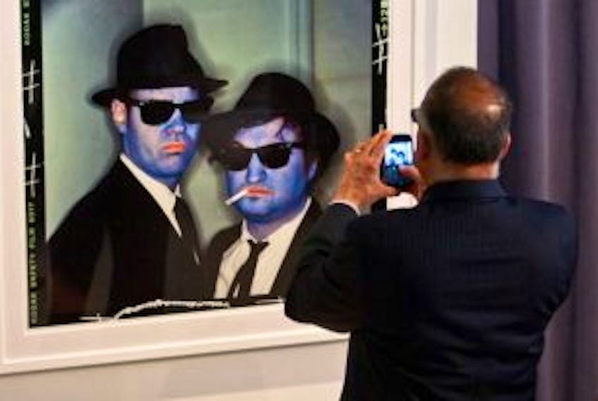 ["Minister Leonard Preyra snaps a photo of Annie Leibovitz's iconic photograph of the Blues Brothers. A large collection of Leibovitz's photos will be added to the permanent collection."]
