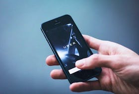 Stock image of hand holding a smartphone displaying Uber app.