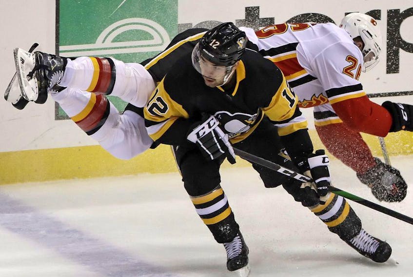 The Pittsburgh Penguins’ Dominik Simon collides with the Calgary Flames’ Michael Stone (26) during a game at PPG Paints Arena in Pittsburgh on Nov. 25, 2019.